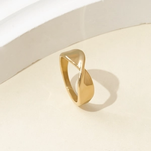 Close-up of a polished gold titanium steel ring with a modern twisted band design