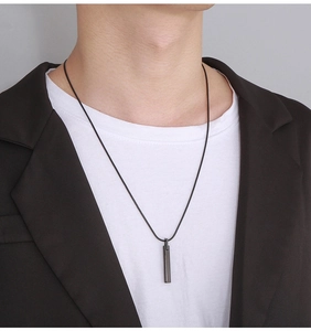 Close-up of minimalist black rectangle pendant with leather cord worn on a model