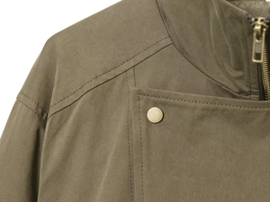Detailed macro view of khaki cotton trench coat featuring metallic buttons and twin-needle stitching