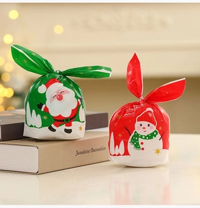 Close-up of rabbit-ear Christmas gift bags with Santa and Snowman prints on books