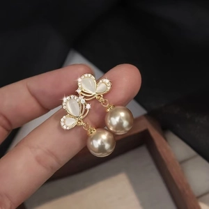 Elegant gold butterfly earrings with sparkling cubic zirconia and large golden pearls