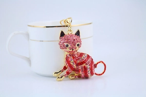 Close-up of a lucky cat keychain with pink and red rhinestones on a gold metal base