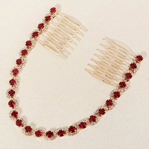 Detail view of gold bridal hair comb with red crystal accents and sparkling rhinestones
