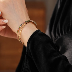 Detail of gold layered open bracelet with rainbow zircons and honeycomb texture