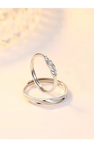 Detailed view of silver Cupid feather couple rings with gemstone and wave pattern