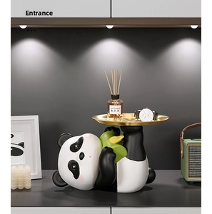 Detail of cute panda sculpture holding a gold tray with keys and watch in home setting