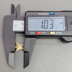 Digital caliper measuring the 10.3mm width of a gold butterfly crystal pendant charm