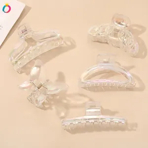 Close-up of five iridescent transparent hair claws in various geometric and butterfly shapes
