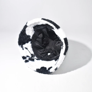 Fuzzy cow print bucket hat in black and white plush material with soft inner lining