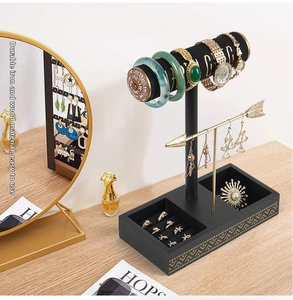 Detail view of double-tier black jewelry stand with gold metal rods and ring slots