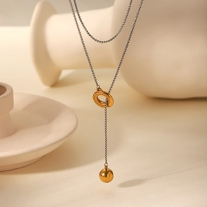 Detail of a two-tone Y-shaped necklace with golden ring and sphere pendant on silver chain