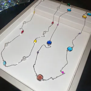 Layered stainless steel necklace with colorful crystal beads and white pearls on a white stand