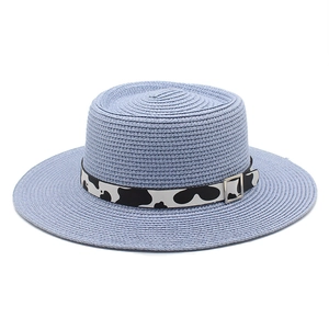 Detail of straw hat with fine texture and black and white cow print ribbon trim