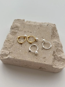Detailed view of 925 silver pearl hoop earrings in gold and silver finish on stone