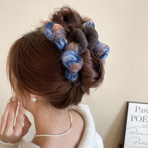 Detail of a plush blue and brown velvet bow hair claw clip worn on a model's hair