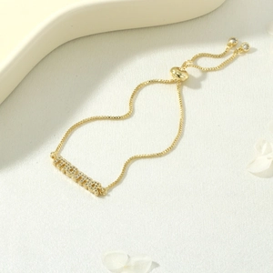 Detail of adjustable gold MAMA bracelet with zircon inlay and elegant bolo slider clasp