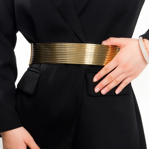Detailopname van een brede gouden elastische riem gestyled over een zwarte jurk