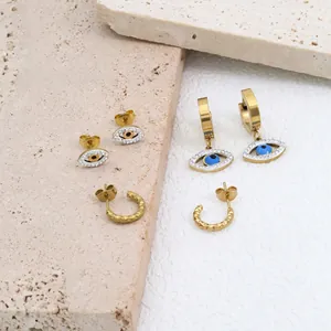 Hip hop evil eye stud earrings set with zircon stones in gold finish on stone surface