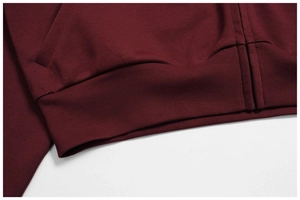 Macro view of burgundy hoodie showing zipper teeth, side pocket stitching, and ribbed hem