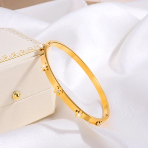 Detail of a gold flower bangle with cubic zirconia on white silk and jewelry box