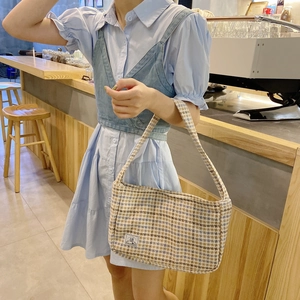 Detail of blue plaid tweed shoulder bag with SR label shown on a model in a cafe setting