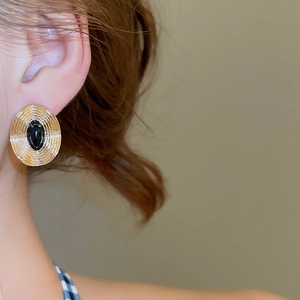 Nahaufnahme von Vintage Gold Metall Ohrsteckern mit schwarzem Stein an einem Modell