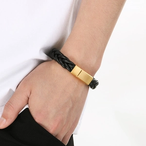 Men's black braided leather bracelet with a polished gold magnetic clasp on a male wrist