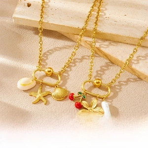 Detail of gold-plated necklaces with starfish, shells, cherries and pearls on stone