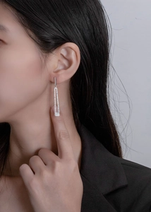 Model wearing silver geometric long tassel earrings with sparkling pavé cubic zirconia