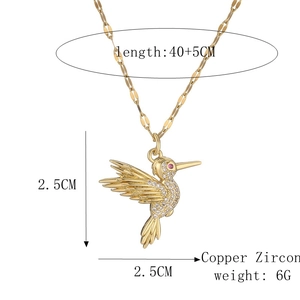 Détail du pendentif colibri doré orné de zircons blancs et d'un œil en pierre précieuse rose