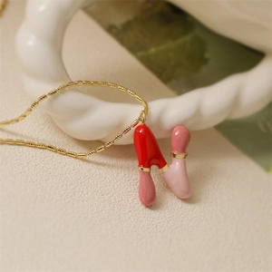 Gros plan détaillé d'un collier doré avec un pendentif lettre N en émail rouge et rose