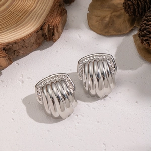 Detailed view of silver shell earrings with rhinestones on a rustic background