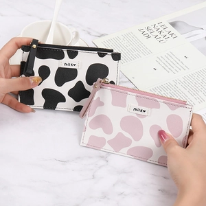 Slim cow print wallets in black and pink with zipper closure on marble background