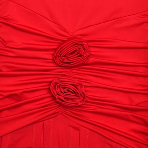 Detailed macro view of red pleated fabric featuring handmade 3D floral rose decorations