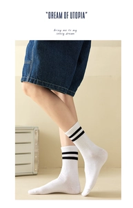 Close-up of white cotton mid-calf socks with black stripes and typography detail