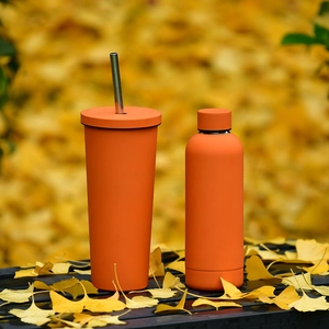 Ensemble bouteille et gobelet en acier inoxydable orange sur des feuilles d'automne