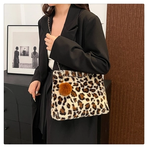 Detail of leopard print plush shoulder bag with silver chain and brown pompom charm