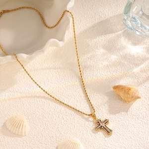Macro shot of gold twist chain necklace featuring a vintage diamond-encrusted cross pendant