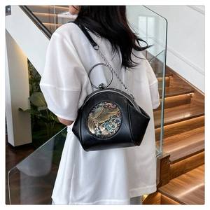 Detail view of the vintage black shell bag featuring a metallic elephant relief and round handle