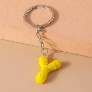 Detail of yellow letter Y keychain with embossed rose pattern on geometric stand