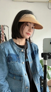 Detailansicht des gewebten Raffia-Sonnenhuts, kombiniert mit einer Jeansjacke