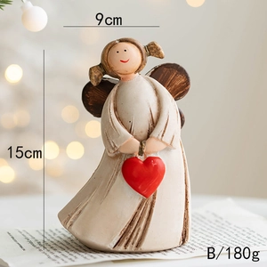Detail of resin angel ornament with red heart, measuring 9cm by 15cm high