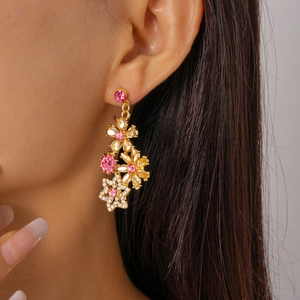 Detailed close-up of pink and champagne crystal floral drop earrings on a model
