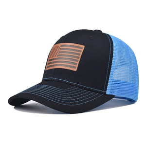 Dettaglio della toppa in pelle con bandiera USA e rete blu traspirante sul cappello trucker