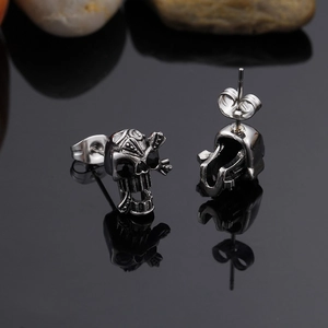 Macro view of punk style silver skull stud earrings with butterfly back on black surface