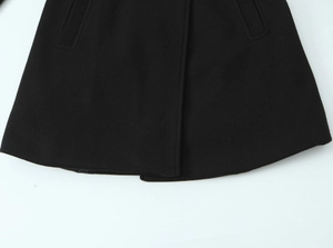Detailed close-up of black blended wool fabric texture and hem stitching on a short coat