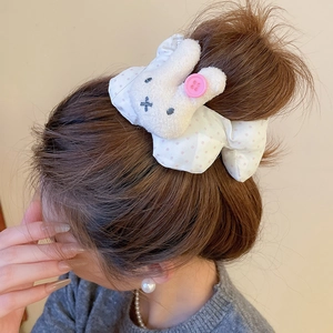Polka dot fabric scrunchie with plush bunny doll on a model's high ponytail hair bun