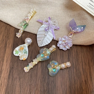 Détail de pinces à cheveux fleurs et cœurs avec perles et strass sur toile de jute