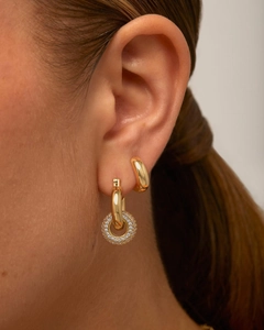 Gros plan de boucles d'oreilles huggie plaquées or 14K avec pendentif zircon sur l'oreille