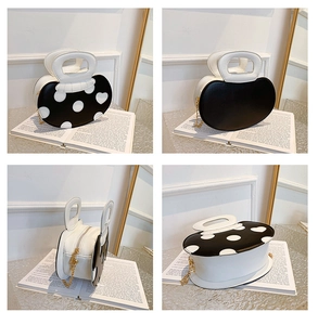 Detail view of round polka dot crossbody bag with gold chain and white handle